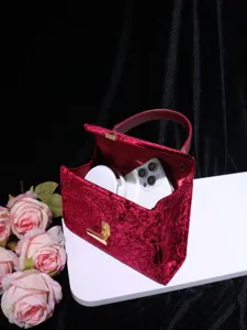 Exquisite red velvet handbag detail, featuring soft plush texture and elegant gold tone hardware.
