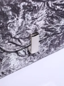 Close-up detail of silver gray textured evening bag clasp and soft fabric surface.