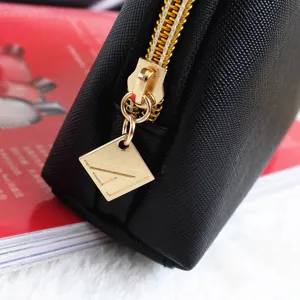 Black Saffiano leather cosmetic bag detail showing durable gold zipper and custom diamond charm.