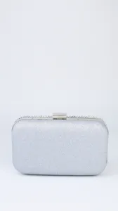 Silver glitter evening clutch bag detail showing sparkling finish and rhinestone metallic clasp.