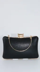 Black evening clutch bag detail shot showing gold metal chain handle and sparkly fabric.