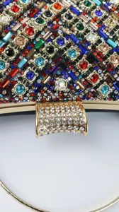 Close-up detail of luxury colorful rhinestone evening clutch bag with gold metal frame lock.