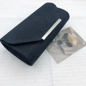 Detailed view of the black glitter evening clutch bag featuring a sleek silver metal closure.