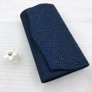 Detail view of dark blue sparkly pleated evening clutch bag with rhinestone texture.