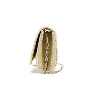Vista di dettaglio laterale di una pochette da sera glitterata dorata con tracolla a catena.