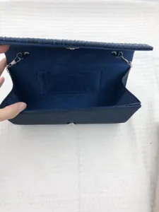 Detailed view of a dark blue glitter evening clutch bag interior with pocket and chain loops.