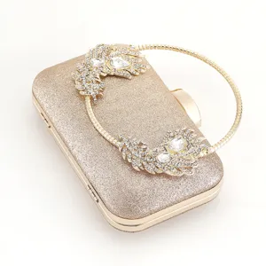 Detail shot of golden glitter evening clutch with rhinestone feather handle and metal frame.