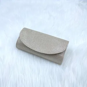 Gold glitter evening clutch bag detail showing sparkling fabric and elegant curved flap design.