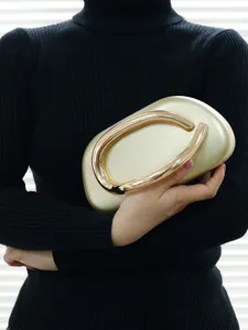 Elegant gold evening clutch bag with metallic sculptural handle detail for special events.