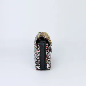 Detailed side view of a luxury rhinestone embellished evening shoulder bag with gold chain.