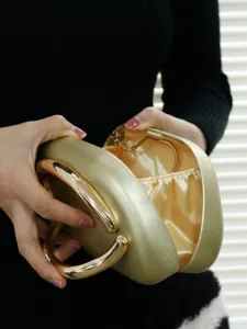 Close-up detail view of gold evening bag showing metal handle and smooth satin interior lining.