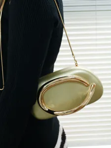 Metallic gold evening clutch bag detail showing elegant metal handle and fine chain strap.
