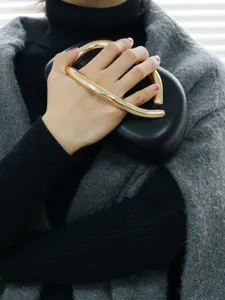 Detail view of a vintage black evening clutch with a unique gold metal handle design.