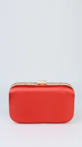 Detailed view of the red satin evening clutch with metallic gold frame and crystal details.