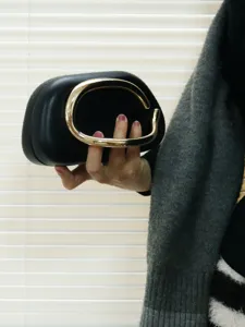 Elegant black clutch bag with statement gold metal handle for evening party and wedding events.