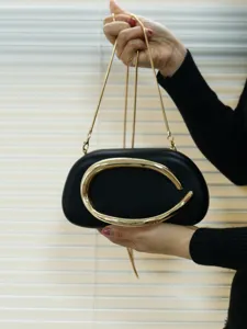 Black oval evening clutch bag with metallic C-shaped handle and gold chain strap for women.