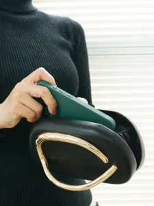 Elegant black evening clutch with distinctive gold metal handle, perfect for banquets and parties.