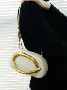 Closeup detail of elegant evening clutch with striking gold abstract ring and metal chain.