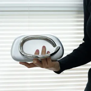 Stunning silver metallic evening clutch bag featuring a unique curved metal handle.
