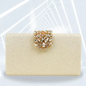 Close-up of gold sparkly evening clutch with crystal gem clasp for party dress.