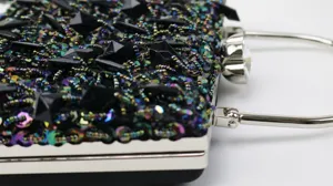Close-up detail of women's evening clutch, sequin beaded rhinestone design with silver frame.