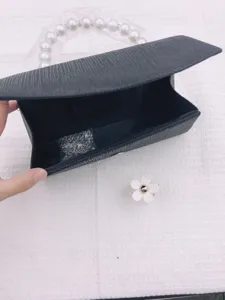 Elegant black evening clutch bag with pearl handle and metal chain strap for women.