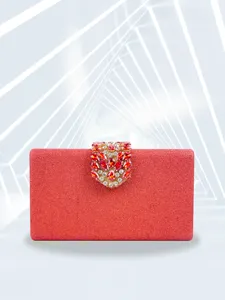 Close-up detail of a stunning red sparkly evening clutch featuring an exquisite ruby crystal clasp.