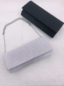 Detailed view of rhinestone pleated evening clutch bag, elegant silver and black design.