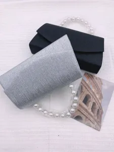 Detail shot of elegant evening clutch bags with pearl handles in black and silver finishes.