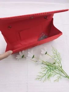 Red pleated evening clutch bag interior detail, featuring a detachable chain strap and inner pocket.