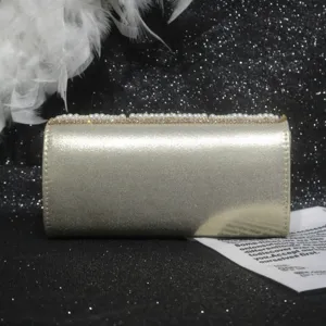 Detail view of the elegant gold evening clutch with delicate pearls and sparkling rhinestones.
