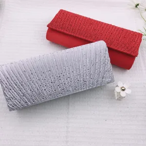 Close-up of elegant rhinestone pleated evening clutch bag, sparkling crystal details for party.