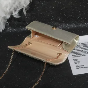 Detail view of a glamorous gold evening clutch bag with pearl trim and metal chain strap.
