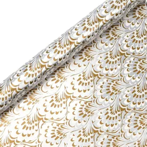 Close-up detail of decorative wrapping paper roll with elegant gold and silver feather pattern.
