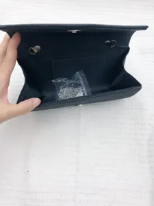 Detailed view inside the black evening clutch bag, showing the chain strap and pocket.