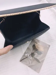 Vue détaillée de la pochette de soirée noire pailletée, poche intérieure et fermeture.