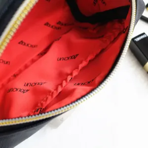 Black Saffiano leather cosmetic bag detail view, red interior lining with zipper and storage pocket.