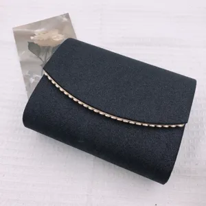 Gros plan d'une pochette de soirée pailletée noire avec bordure dorée sur fond blanc.