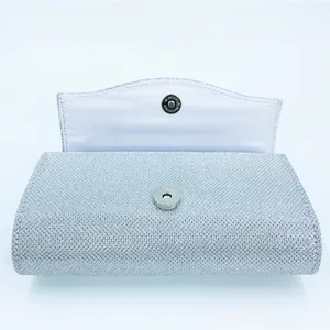 Silver glitter evening clutch bag detail showing magnetic snap closure and texture