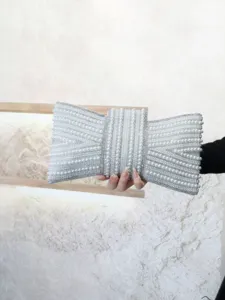 Close-up of elegant pearl bow evening clutch bag, sparkling rhinestone details for party.
