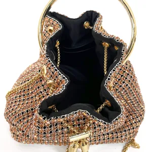 Detailed shot of sparkling rhinestone bucket evening bag with gold round handle and chain strap.