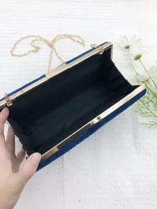 Detail view of the blue velvet evening clutch bag with golden metal frame and chain strap.