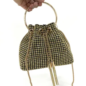 Detailed shot of sparkling gold rhinestone bucket bag with metal ring handle and chic chain strap.