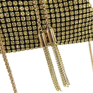 Detail shot of sparkling gold rhinestone evening bag with metallic chains and tassel charms.