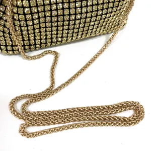 Close-up detail of luxury gold rhinestone evening bag sparkling crystals and metallic chain strap.