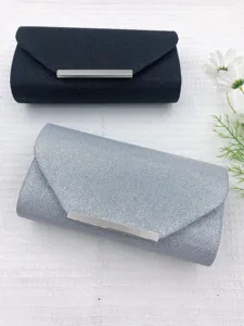 Glitter evening clutch bag detail showing black and silver colors with metal bar closure.