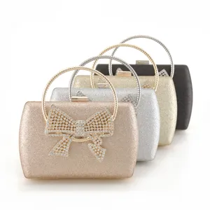 Close-up of sparkling glitter evening clutch with crystal rhinestone bow and metal ring handle.