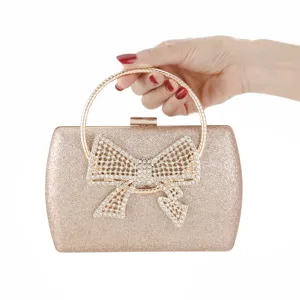 Sparkling gold evening clutch bag detail with rhinestone bow and round metal handle.