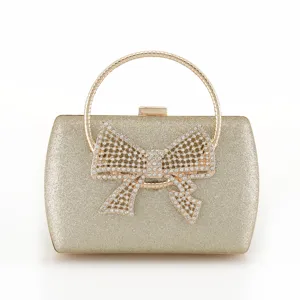 Elegant gold glitter evening clutch with round metal handle and sparkling rhinestone bow.