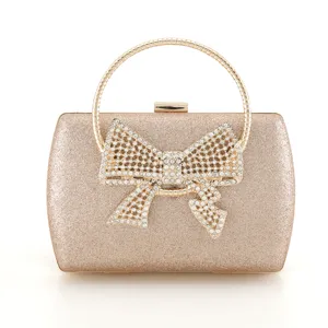 Elegant gold glitter evening clutch bag with sparkling rhinestone bow and round metal handle.
